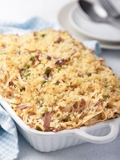 a casserole dish with noodles and meat in it sitting on a blue napkin