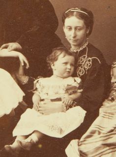 an old black and white photo of two women and a baby sitting on a bed