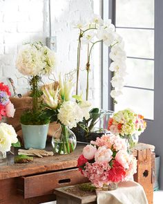 flowers are arranged in vases on an old table