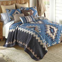 a bed with a blue and brown comforter on top of it in a bedroom