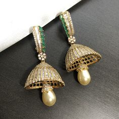 Golden Cubic Zirconia Jhumka earrings with Pearl Drop Made in Brass with Gold Finish Handcrafted with very high quality CZ Stones Length: Approx. 2.65" Earrings come with push back closure Very Lightweight earrings Suitable for any traditional or modern attire Gold Chandbali Jhumkas With Cubic Zirconia, Gold Cubic Zirconia Chandbali Jhumkas, Temple Jewelry American Diamond Jhumkas For Reception, Gold Bollywood Jhumkas With Cubic Zirconia, Gold Cubic Zirconia Bollywood Jhumkas, Heavy American Diamond Jhumkas For Reception, Cubic Zirconia Chandbali Jhumkas For Reception, Bollywood Style American Diamond Jhumkas For Formal Occasions, American Diamond Chandbali Jhumkas For Reception