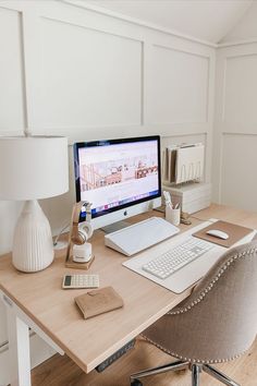 a desk with a computer, lamp and phone on it