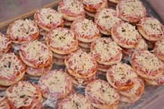 many small pizzas with cheese and sauce on them