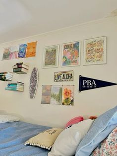 there are many pictures on the wall above the bed in this room, including books and magazines