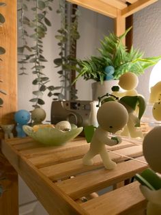 a wooden table topped with small figurines and potted plants in front of a mirror