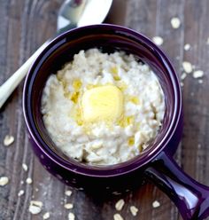 a bowl of oatmeal with a buttered egg on top and spoon next to it