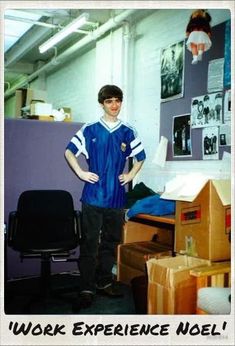 a young man standing in an office with his hands on his hips