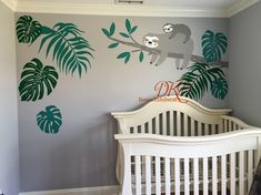 a baby's room with a white crib and green leaves on the wall