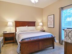 a bed room with a neatly made bed and two night stands next to a window