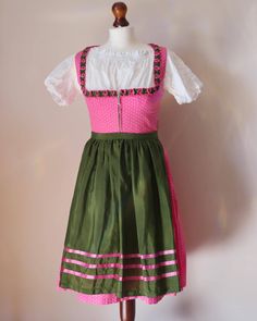 Vintage dirndl dress with an apron, size 36 EU. Women's traditional Oktoberfest dress with a floral dot print in pink and white. The dress has a zip bodice with frilled neckline with green details. The flared skirt falls free below the knees. The dress comes with a matching green cotton apron with pink satin detailing. Please note that the white blouse from the photos in not included! Brand: Steindl Material: 100% Cotton, Apron is Cotton and Satin Size: 36 EU, which is 6 US or S and UK 8 or S. Oktoberfest Dress, Green Apron, Green Details, Dirndl Dress, Cotton Apron, Fall Skirts, Pink Satin, White Blouse, Cottage Core