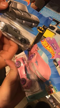 a person holding a pink toy car in their hand and it's packaging on the table