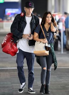 the man and woman are walking together through an airport terminal with their luggage bags in hand