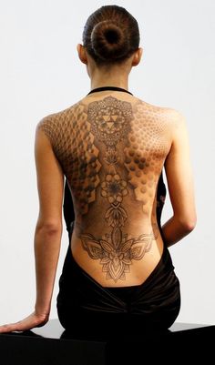 the back of a woman's body with tattoos on her upper and lower back