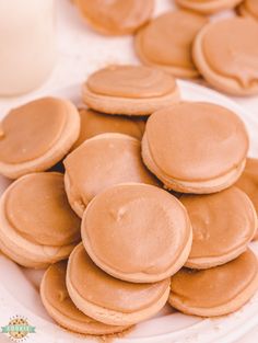 a plate full of pancakes on a table with a glass of milk in the background