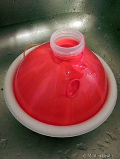 a red and white bowl sitting on top of a metal sink