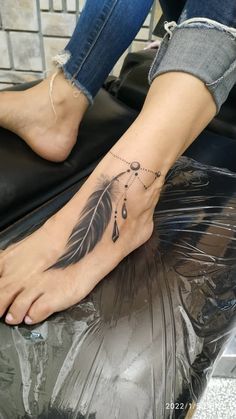 a woman's foot with a feather tattoo on it