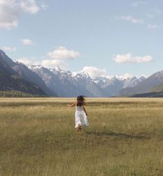 a girl in a field with mountains in the background