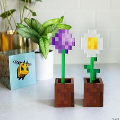 two lego planters sitting on top of a table next to a potted plant