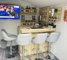 a bar with three stools in front of it and a television on the wall