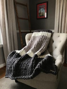 a chair with a blanket on top of it in front of a window next to a ladder