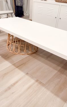 a large white table sitting on top of a hard wood floor next to a cabinet