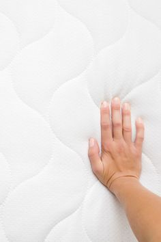 a person's hand on top of a mattress