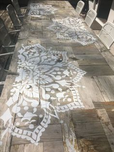 the table is covered with white stencils on it's wood planks