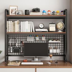 a desk with a computer, books and other items on it in front of a white wall