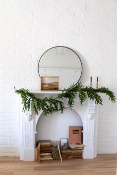 a white fireplace with a mirror above it and books on the mantel next to it