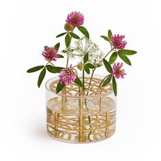 a glass vase filled with pink flowers on top of a white table next to a plant