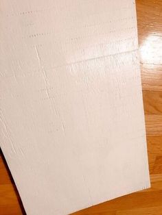 two pieces of white paper sitting on top of a wooden floor