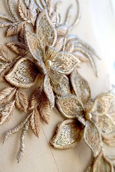 a close up view of the back of a dress with gold embroidered flowers on it