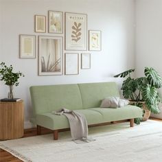 a green couch sitting in front of a white rug on top of a wooden floor