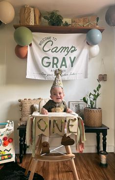 a baby sitting in a high chair with a party hat on