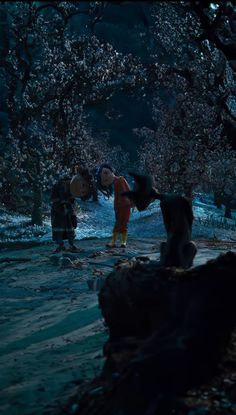 two people standing in the middle of a forest at night with trees and flowers all around them