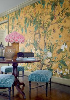 a dining room table with blue chairs and a wallpapered area in the background