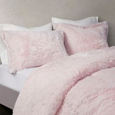 a bed with pink pillows and blankets on it