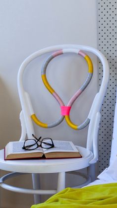 a pair of glasses sitting on top of an open book next to a white chair