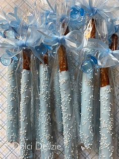 blue and white candy sticks wrapped in clear cellophane with bows on the ends