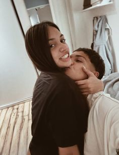 a young man and woman cuddle together on the bed