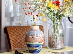 a vase filled with flowers sitting on top of a table next to a glass vase