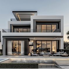 an exterior view of a modern house with pool in the foreground and lounge area