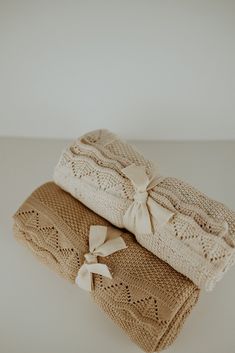 two knitted blankets with bows on them sitting on top of a white countertop