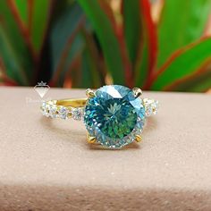 a blue diamond ring sitting on top of a table next to a potted plant