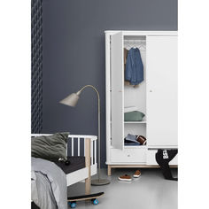 a room with a bed and a white armoire in front of a gray wall