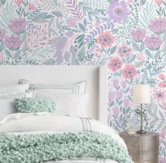 a bedroom with floral wallpaper and bedding in pastel colors, including pink flowers