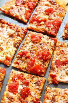 square slices of pizza with tomatoes and cheese on a baking sheet ready to be eaten