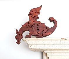 a wooden dragon sculpture sitting on top of a fireplace mantel next to a white wall