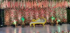 the stage is decorated with red and pink flowers, green lights, and a white bench