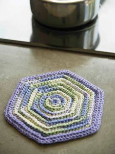 a crocheted coaster sitting on top of a counter next to a pot holder